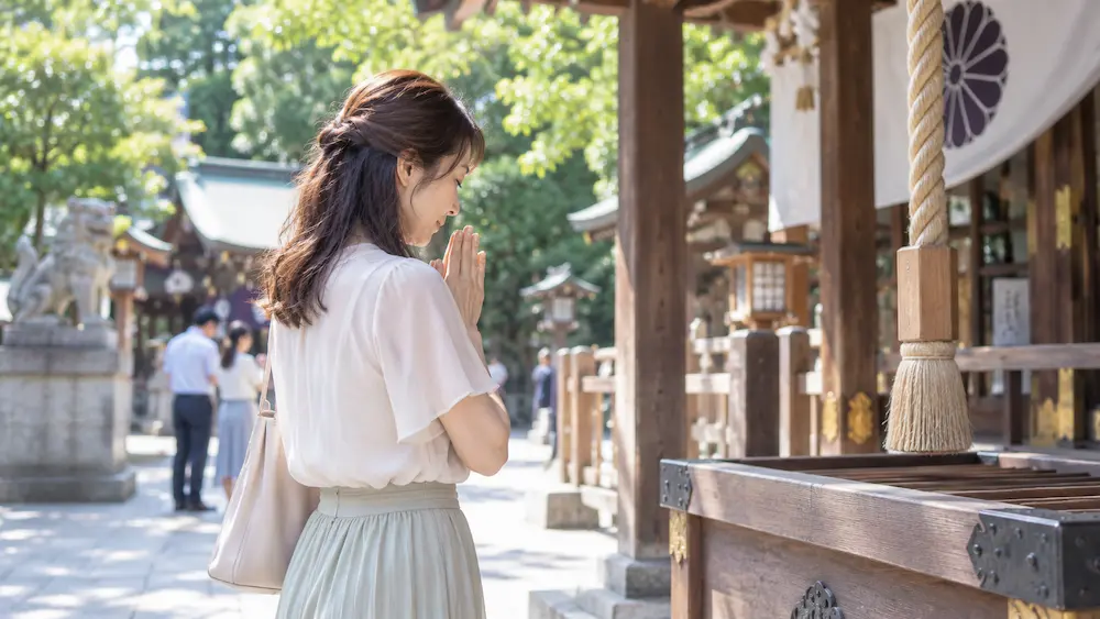婚活に悩み運命の人との出会いを願って神社で手を合わせる女性